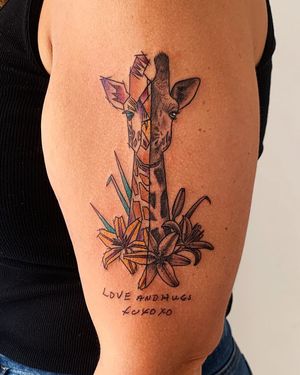 Get a unique watercolor tattoo of a giraffe intertwined with colorful flowers on your upper arm at a top tattoo studio in New York City.