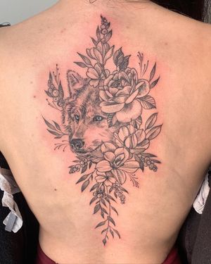 Illustrative blackwork tattoo featuring a wolf and flower on the back, located in New York, US.