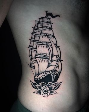Get a stunning blackwork tattoo of a ship and flower on your ribs in Miami for a unique and artistic look.