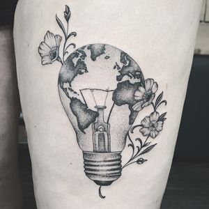 Express your wanderlust with a unique blackwork and illustrative tattoo featuring a flower, lamp, map, and world design on your upper leg in Miami.