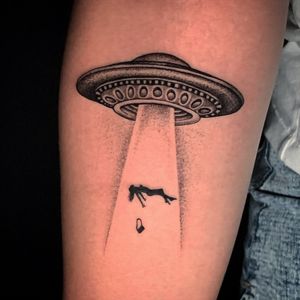 Get inked with a striking blackwork tattoo featuring a UFO, spaceship, woman, and purse on your forearm in Miami.