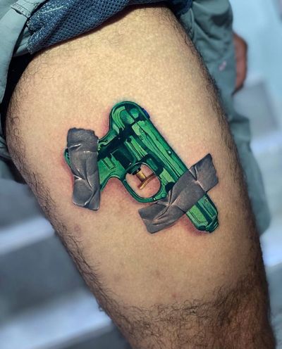 Get a bold and vibrant new school gun tattoo on your upper leg in Miami, US. Stand out with this illustrative design!