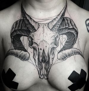 Bold blackwork chest tattoo featuring an illustrative skull with horns by Rico Dionichi. Stand out with this unique design.