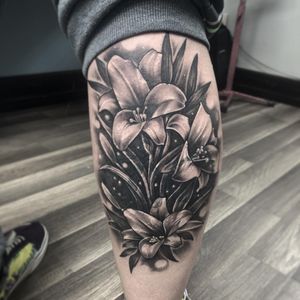 Bold and intricate flower design on lower leg, expertly executed with illustrative style by tattoo artist Rico Dionichi.