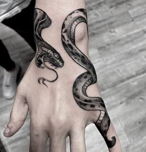 Unique blackwork design by tattoo artist Rico Dionichi, featuring a detailed snake motif on the hand.