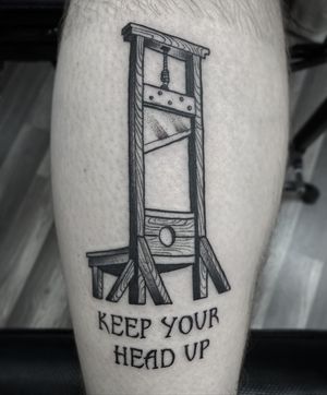 Rico Dionichi's blackwork forearm tattoo features a guillotine illustration with a powerful quote. A bold and rebellious statement piece.
