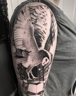 Captivating blackwork upper arm tattoo featuring a detailed owl perched on a book, expertly done by Rico Dionichi.