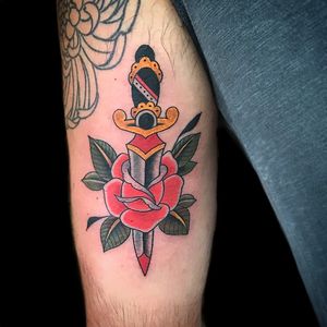 Check out this traditional style upper arm tattoo featuring a beautiful flower and menacing dagger, done by Chris Tambo.