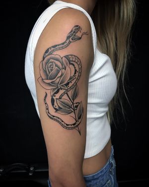 A bold blackwork and illustrative tattoo featuring a snake and flower design, expertly executed by tattoo artist Chris Tambo.