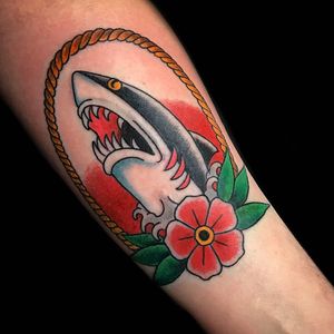 Impressive traditional forearm tattoo featuring a shark, flower, waves, and rope motifs by Chris Tambo.