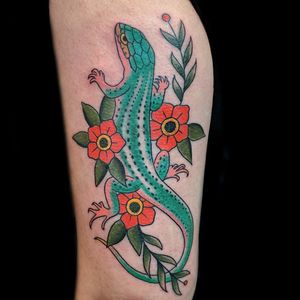 Beautiful upper arm tattoo combining sakura blossoms and a chameleon, created by artist Chris Tambo.