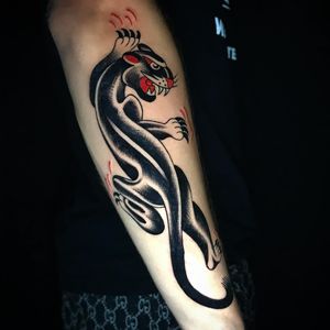 Get a fierce classic panther tattoo on your forearm by talented artist Chris Tambo. Bold blackwork and illustrative style.