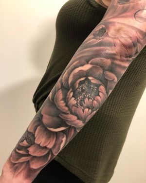 Adorn your arm with a stunningly detailed peony tattoo in black and gray realism by the talented artist Corei. Perfect for adding a touch of nature to your sleeve.