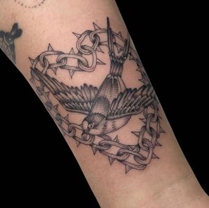 Capture the essence of London with this stylish black and gray tattoo featuring a bird and chain motif on your forearm.