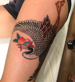 Traditional style tattoo featuring a vibrant fruit motif and majestic heron, beautifully inked on upper leg in London.