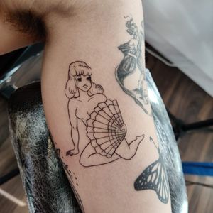 Elegant illustrative tattoo featuring a girl with a fan on upper arm. Perfect for those in London seeking unique and refined body art.