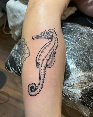 Get an exquisite fine line seahorse tattoo on your forearm in London. This delicate design will make a statement with its intricate details.