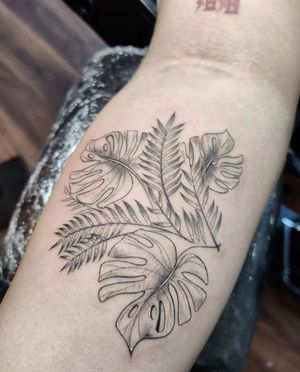 Elegant fine line floral tattoo featuring a white ink monstera leaf on the forearm. Perfectly crafted in London, GB.