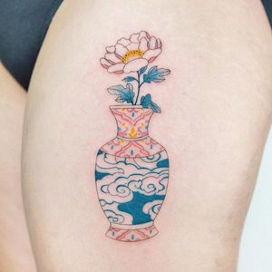 An illustrative flower and vase tattoo beautifully inked on the upper leg in London, GB.