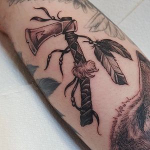 Blackwork illustrative tattoo by Dani Mawby featuring a feather and axe motif.
