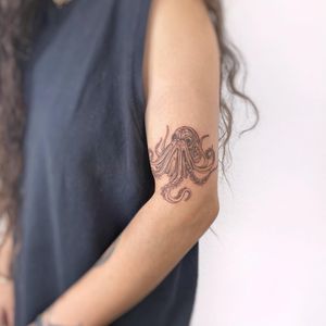 Get a stunning illustrative octopus tattoo on your upper arm by the talented artist Polina. Embrace fine line art with this unique design!
