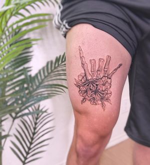 Elegant blackwork tattoo by Polina featuring a delicate flower, hand, and skeleton design on upper leg.
