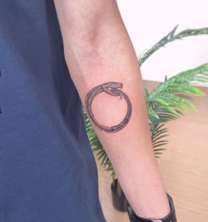 Adorn your forearm with a stunning fine line and illustrative snake ouroboros tattoo created by the talented artist Polina.