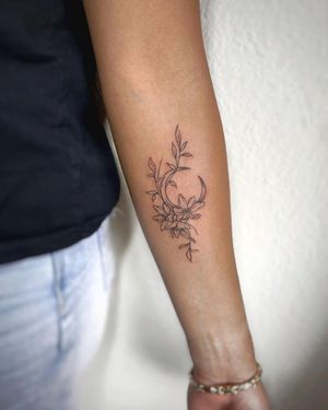 Polina's illustrative design features a delicate moon and flower motif, beautifully placed on the forearm.