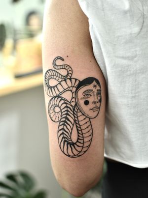 Express your love for snakes with this striking blackwork tattoo on your upper arm. Visit ALEJANDRO for unique designs!