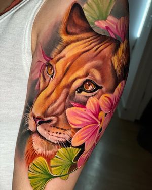 Vibrant and lifelike upper leg tattoo featuring a fierce lioness surrounded by beautiful flowers, perfect for Miami vibes.