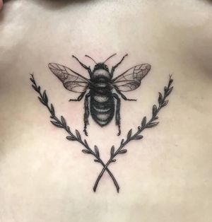 Illustrative blackwork design by Jose Cordova, showcasing a beautiful bee, flower, and sprig motif on the sternum.