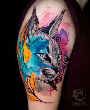 Beautiful upper arm tattoo by Alex Santo featuring a geometric watercolor design of a lynx cat and intricate patterns.