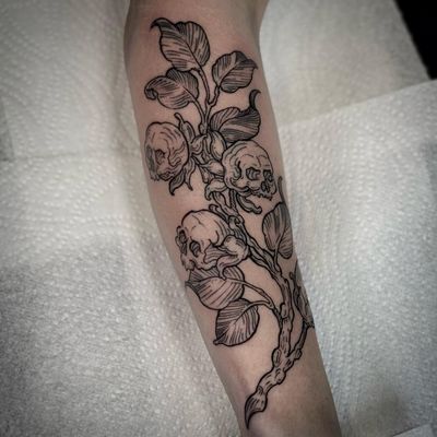 Beautiful black and gray fine line tattoo featuring a skull, leaf, and branch design, expertly done by Lamat.