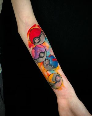 A striking forearm tattoo by Sandro Secchin featuring a vibrant anime style pokeball design in watercolor motif.