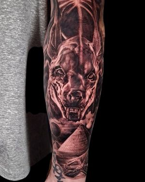 Impressive black and gray forearm tattoo of Anubis standing next to a pyramid, expertly done by Mauro Imperatori.