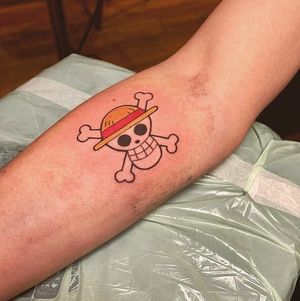Vibrant new school tattoo on forearm featuring a stylized anime skull wearing a hat, by artist Frankie Brown.