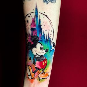 Get a magical vibe with this illustrative watercolor tattoo featuring Mickey Mouse and a castle, created by Marcel Oliveira.
