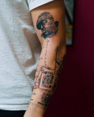 Gabriele Edu's micro-realism arm tattoo featuring a cap, quote, and iconic rap figure, Notorious BIG.