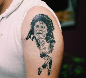 Gabriele Edu expertly blends micro-realism and illustrative styles to create a striking black and gray tattoo of Michael Jackson's iconic legs on the upper arm.