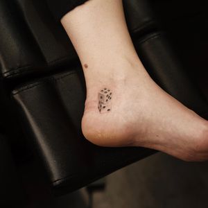 Gabriele Edu's fine line illustrative tattoo of realistic dice on the ankle in black and gray.