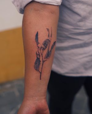 Gabriele Edu's black and gray micro-realism tattoo combines a beautiful flower with the image of a mysterious woman, creating a surreal and illustrative piece perfect for your forearm.