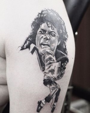 Gabriele Edu beautifully captures the essence of music and Michael Jackson in this detailed black and gray upper arm tattoo.