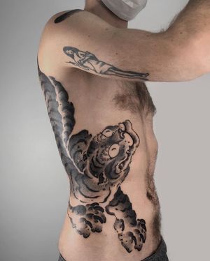 Experience the power and beauty of a Japanese blackwork and dotwork tiger tattoo by FKM TATTOO on your ribs.