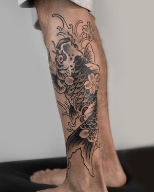 Stunning blackwork tattoo featuring a koi fish, waves and flowers on lower leg by FKM TATTOO.
