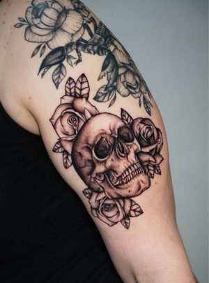 Get a stunning upper arm tattoo featuring a blackwork flower and skull design by expert tattoo artist Miss Vampira.