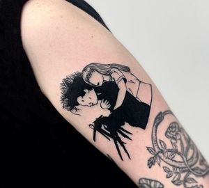 A striking blackwork and illustrative tattoo of Edward Scissorhands with a girl, expertly done by Miss Vampira on the upper arm.