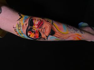 Get motivated with this colorful new school tattoo on your forearm featuring a powerful quote and a bold man design by Marie Terry.