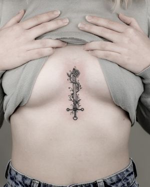 Tatuaj alb-negru între sâni cu sabie A Touch Of Ink