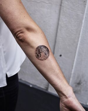 Bold blackwork moon tattoo on forearm, illustrated by Jamie B. Embrace the cycles of life with this stunning design.