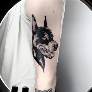 Express your love for man's best friend with a bold blackwork tattoo by Jamie B. This detailed design will stand out on your upper arm.